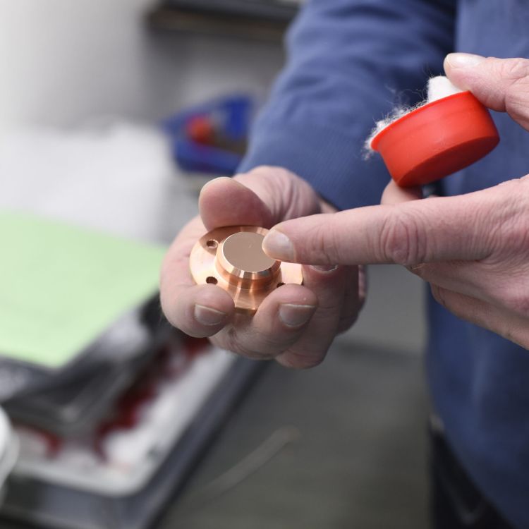 Overfladebehandlet metalkomponent i hånden på en operatør.